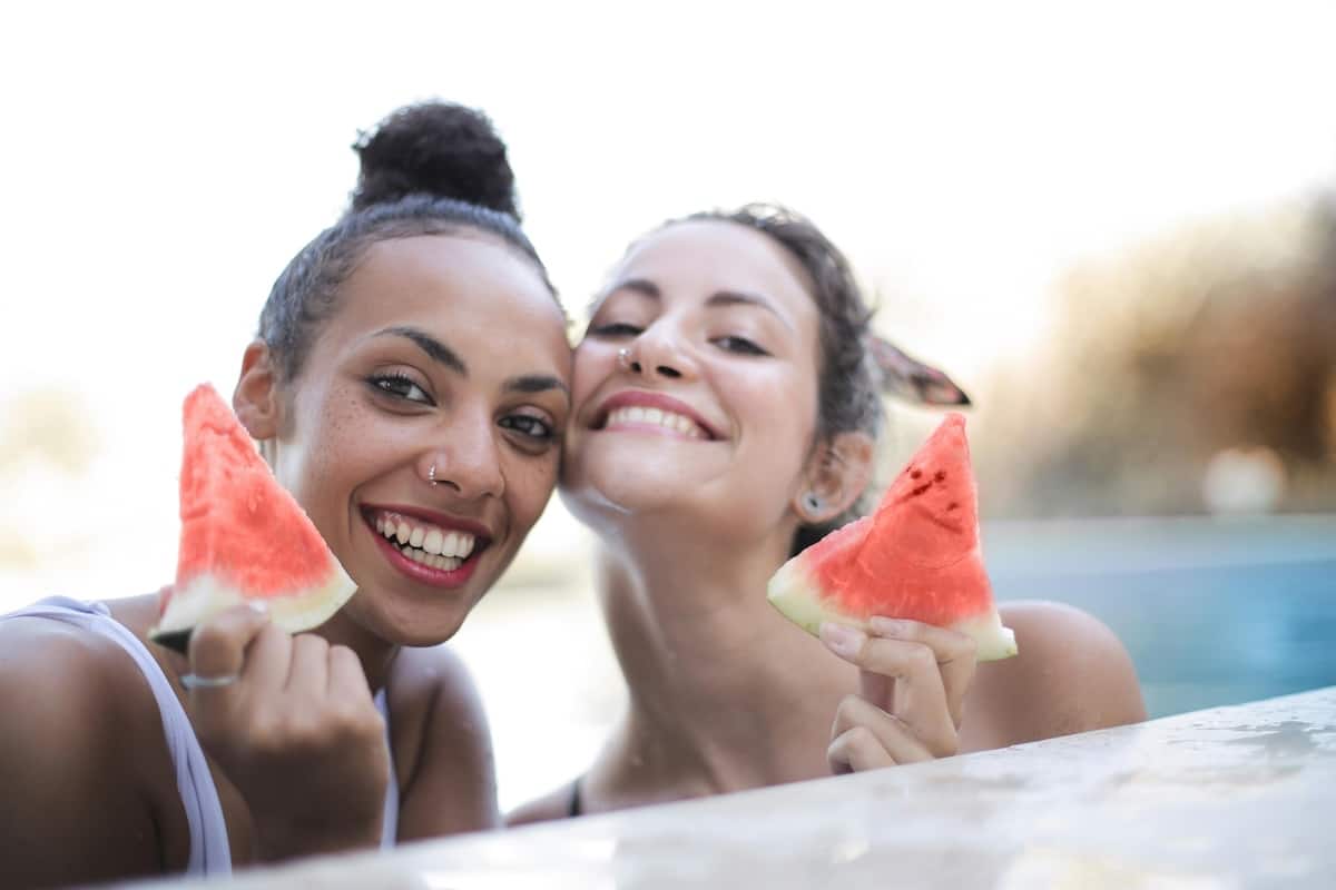 2 Freundinnen sind im Pool und essen eine leckere Wassermelone und freuen sich