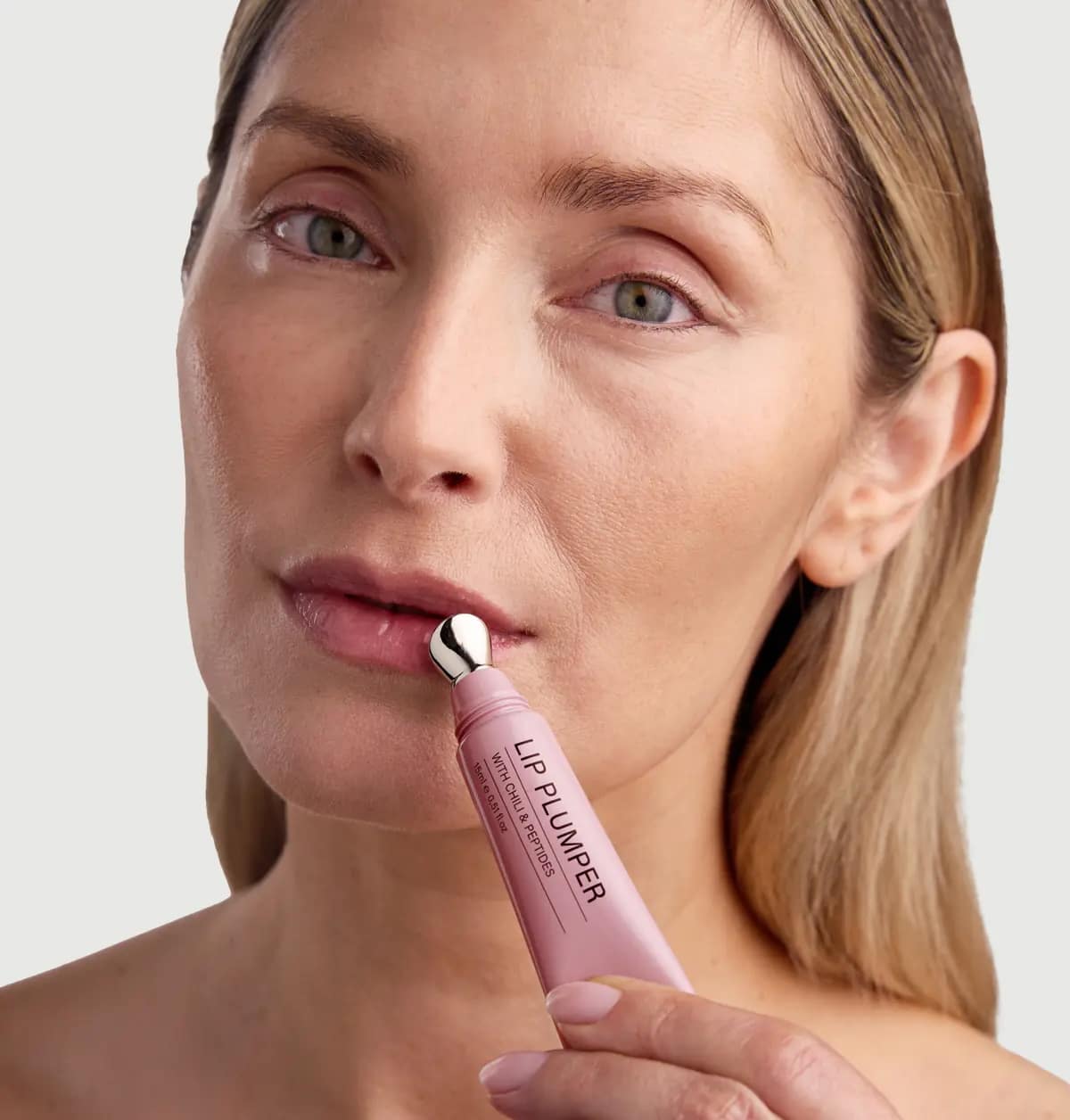 Echte Rosental Organics Lip Plumper Erfahrungen und Testergebnisse – inkl. aktuellem Rabattcode. Frau trägt den Rosental Organics Lip Plumper mit dem Applikator auf die Lippen auf.